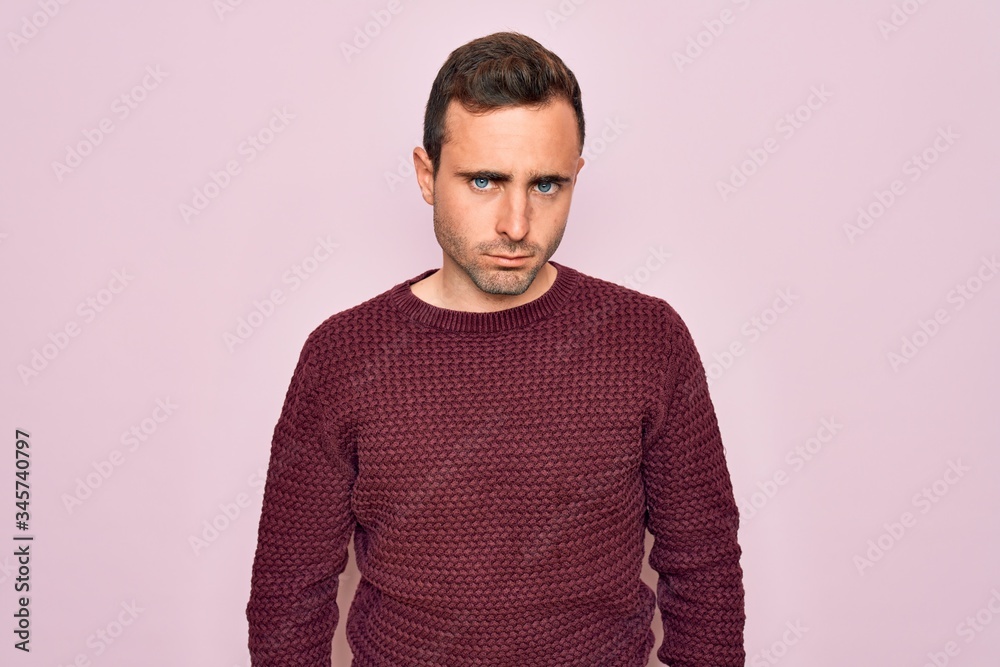 Young handsome man with blue eyes wearing casual sweater standing over pink background skeptic and nervous, frowning upset because of problem. Negative person. Young handsome man with blue eyes wearing casual sweater standing over pink background skeptic and nervous, frowning upset because of problem. Negative person.
