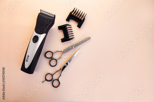 Barber clipper, scissors for haircuts, nozzles for haircuts on a pale pink background. Free space for text. Barber tool. Hairdressing Tools Isolates.