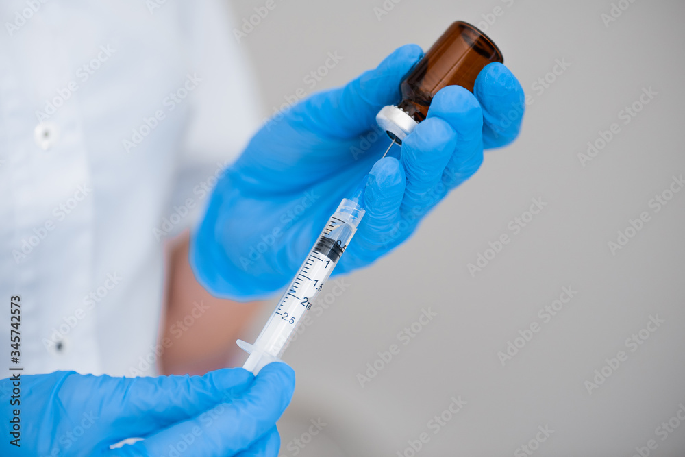 The doctor draws a close-up shot of a vaccine injection into a syringe. The doctor draws a close-up shot of a vaccine injection into a syringe.