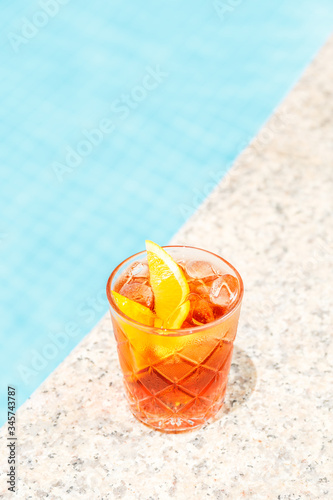 Negroni cocktail near a pool at the resort bar or suite patio. Luxury resort, vacation, holiday, getaway, summer time, room service concept. Vertical