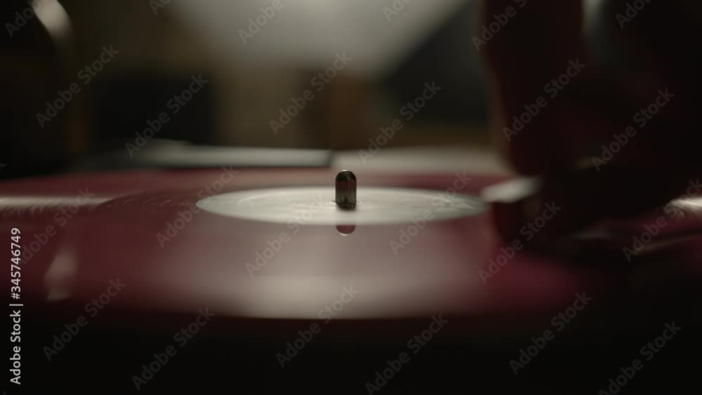 Putting a red vinyl record on turntable and putting stylus needle on