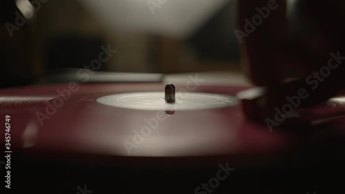 Putting a red vinyl record on turntable and putting stylus needle on