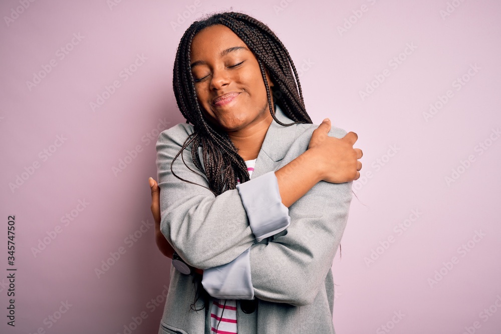 Young african american business woman standing over pink isolated background Hugging oneself happy and positive, smiling confident. Self love and self care