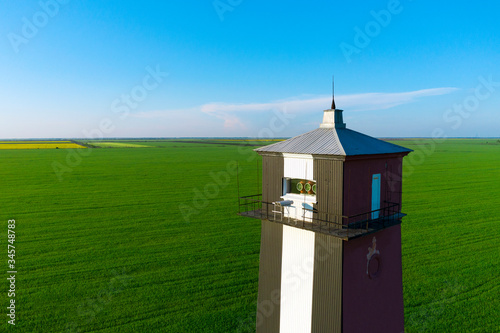 Old lighthouse with red stripes in spring field. Scenic landscape with a tall lighthouse. photo