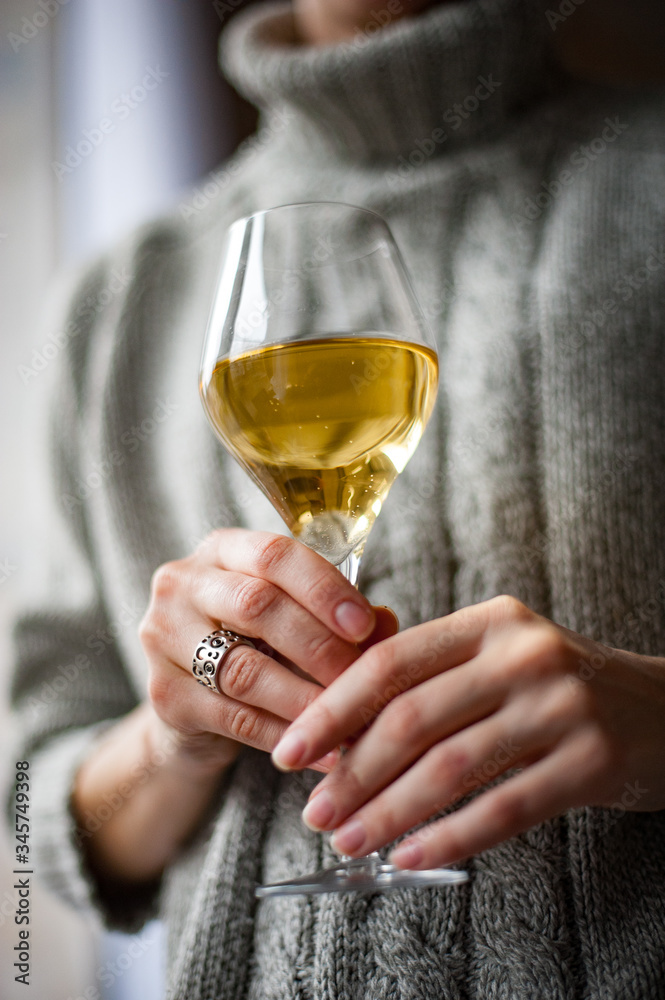 A girl stands by the window with a glass of wine A girl stands by the window with a glass of wine