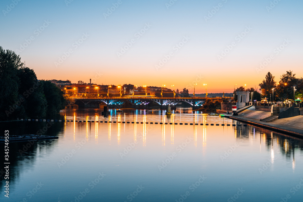 River on the background of the evening city. Panorama of the city from the river pier. Road bridge over the river