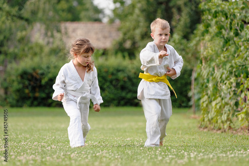 Young karate girl and boy train on the grass in backyard of home