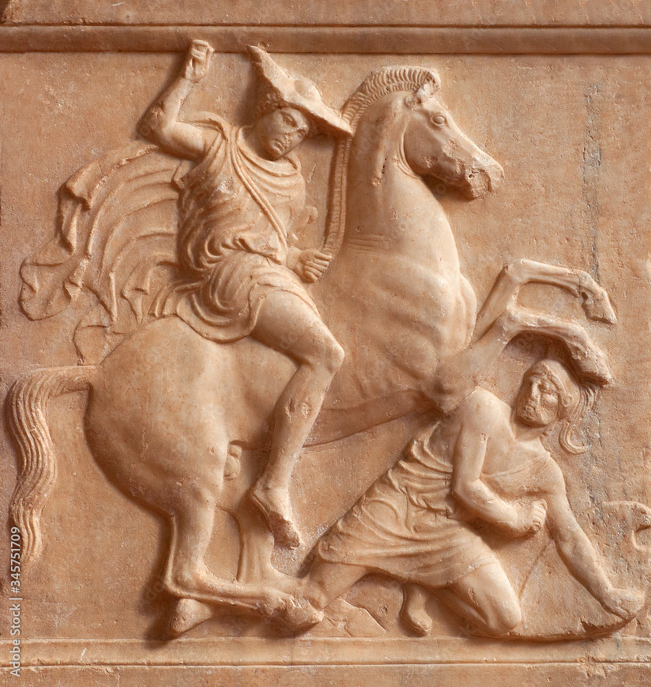 Ancient Greek bas-relief on grave stele depicting battle scene between a rider, the deceased, and a fallen hoplite, a heavily armed foot soldier of ancient Greece. Ancient Greek bas-relief on grave stele depicting battle scene between a rider, the deceased, and a fallen hoplite, a heavily armed foot soldier of ancient Greece.