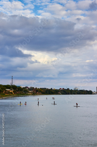 Group of young people Paddleboarding (SUP paddle). Stand up paddle, in Danube river at sunset