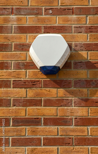 Burglar alarm box and light attached to the wall of a house photo