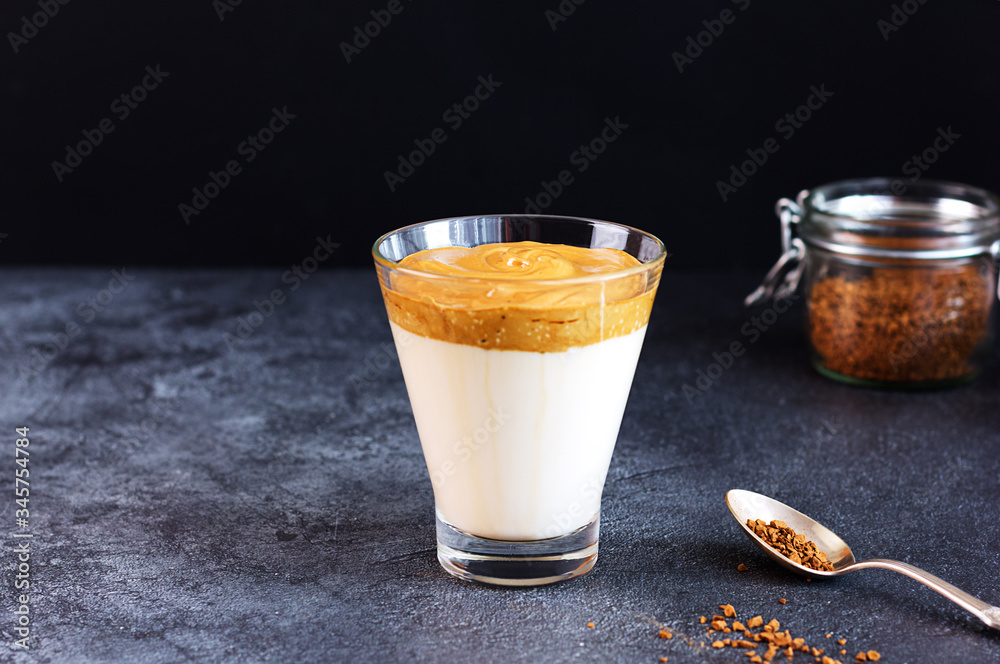 Dalgon coffee is a trendy drink from Korea. Milk and lush coffee foam in a glass against a dark background. Dalgon coffee is a trendy drink from Korea. Milk and lush coffee foam in a glass against a dark background.