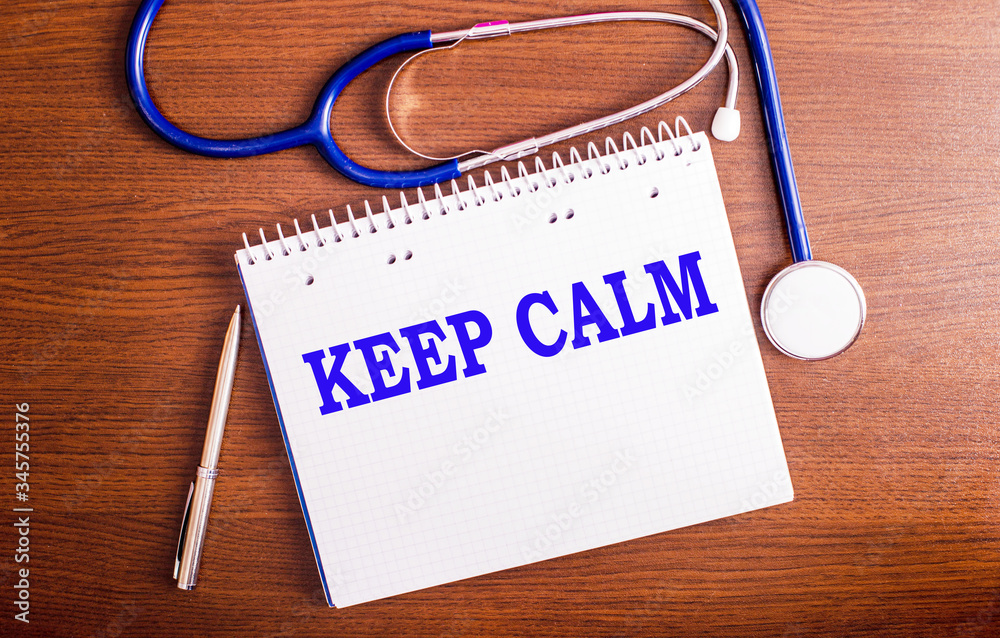 Keep calm-writing on a white sheet on a brown table with a stethoscope Keep calm-writing on a white sheet on a brown table with a stethoscope