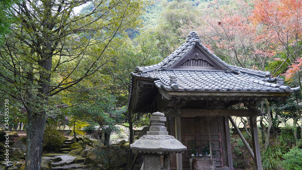 traditional Japanese garden during fall season, stone house amid bright deciduous trees in Sengan-en Park, residence of Shimazu family. historical architecture, stone lamps, pagoda Kagoshima Japan