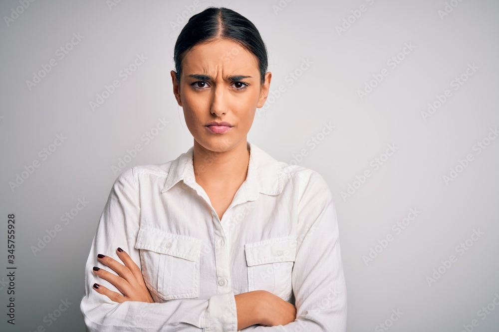 Young beautiful brunette woman wearing casual shirt over isolated white background skeptic and nervous, disapproving expression on face with crossed arms. Negative person. Young beautiful brunette woman wearing casual shirt over isolated white background skeptic and nervous, disapproving expression on face with crossed arms. Negative person.