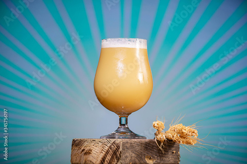 Платно Poured glass of a creamy, hazy India pale ale craft beer from a small micro brewer, with a bright blue and purple pop background