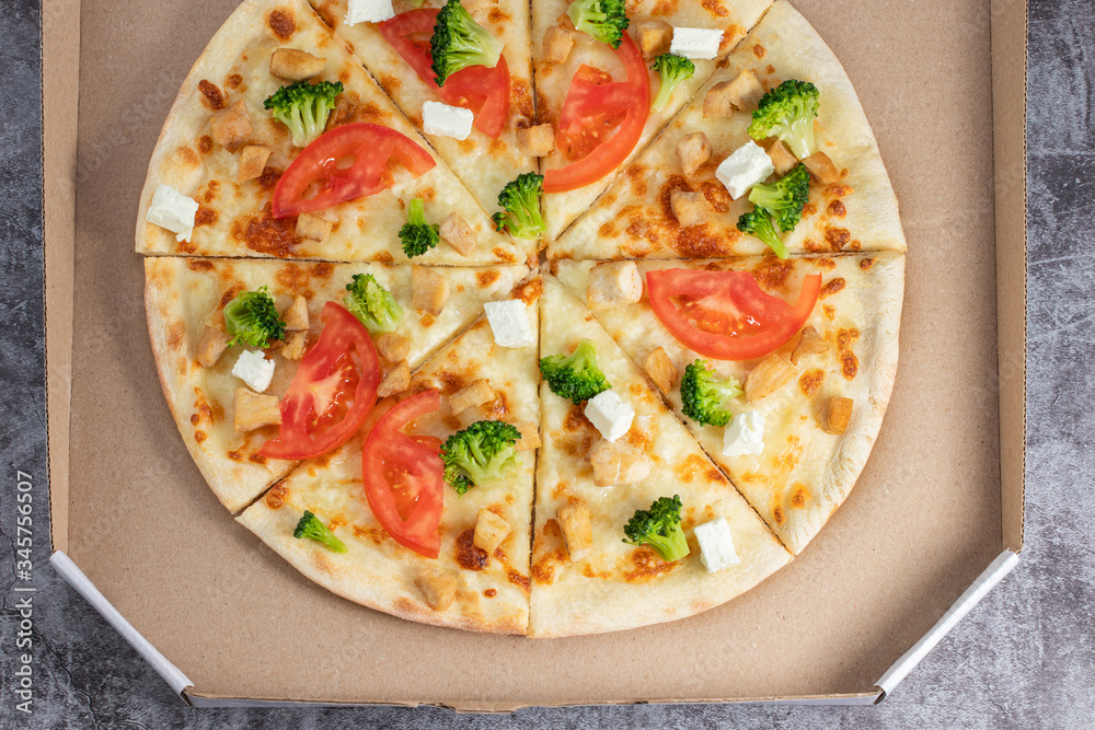 Pizza in a cardboard box against a dark background. View from above. Pizza delivery. Pizza menu