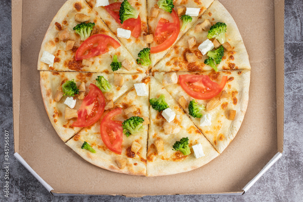Pizza in a cardboard box against a dark background. View from above. Pizza delivery. Pizza menu Pizza in a cardboard box against a dark background. View from above. Pizza delivery. Pizza menu