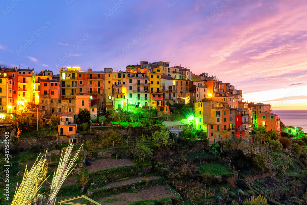 Fototapeta premium Evening panorama of the medieval town of Cornilla in the Cinque Terre National Park in November, purple sunset and colorful houses in Liguria