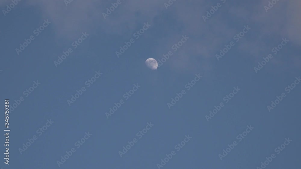 A time-lapse image of the moon flowing across a blue sky and in places overlaid with clouds A time-lapse image of the moon flowing across a blue sky and in places overlaid with clouds