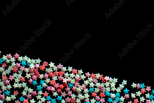 multicolored confectionery sprinkle in the form of stars on a black background