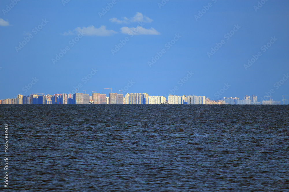 modern high-rise buildings and construction cranes under the blue sky on the seashore