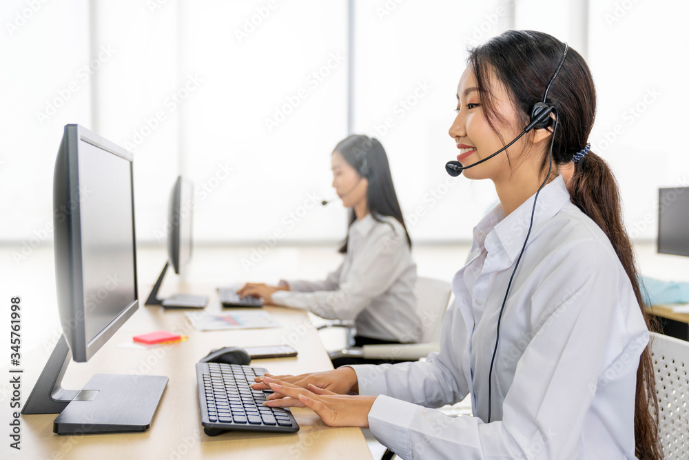 Asian operator woman working in a call center, Female technical support answering customer questions, Customer service using a headset, Concept of Business telemarketing and communication support Asian operator woman working in a call center, Female technical support answering customer questions, Customer service using a headset, Concept of Business telemarketing and communication support