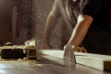 A man cuts wood on a circular saw in a joinery