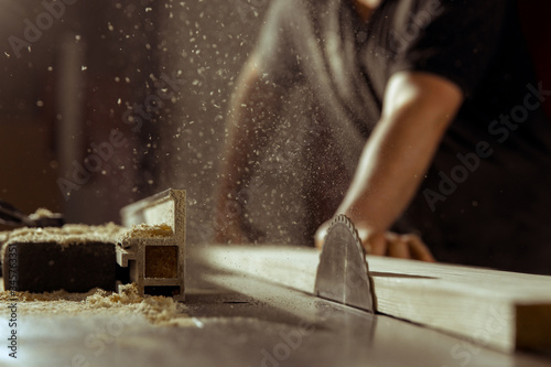 A man cuts wood on a circular saw in a joinery photo
