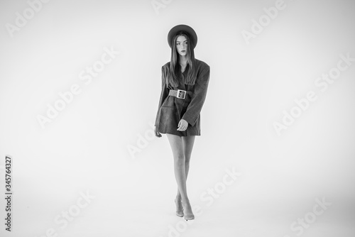 Attractive young girl, model looking to the side in a gray jacket and holding a hat in his hands. Men's style clothing. isolated on a white background. there is a place for an inscription on the side. © Jurii