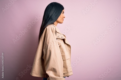 Young beautiful hispanic fashion woman wearing winter jacket and sweater over pink background looking to side, relax profile pose with natural face with confident smile. © Krakenimages.com