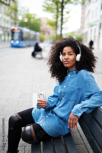 Lässige junge Frau mit Afro und Kopfhörern  © Wellnhofer Designs