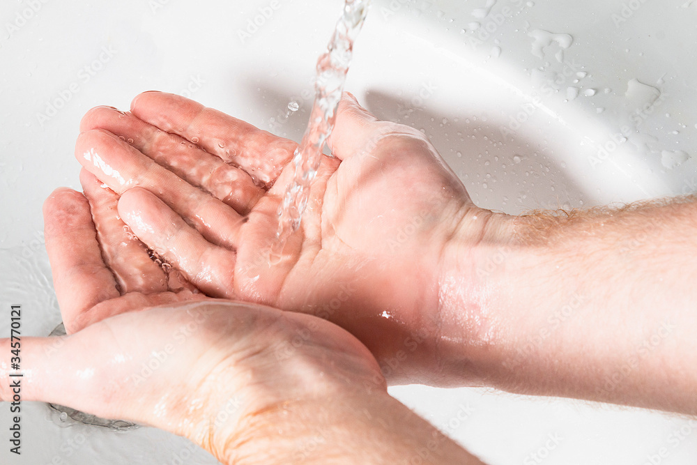 Man use soap and washing hands under the water tap. Hygiene concept hand detail.