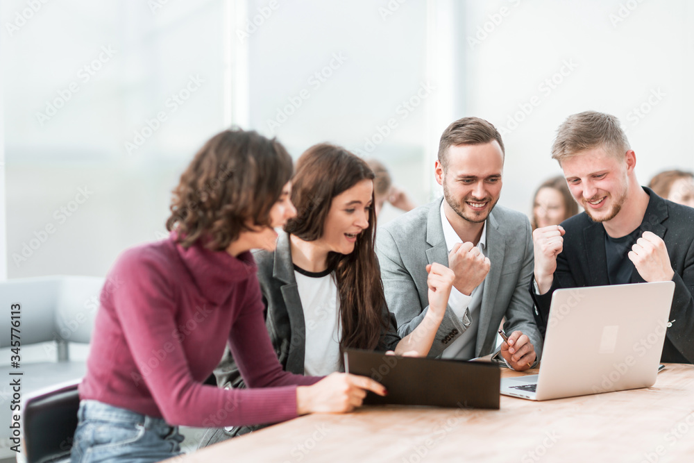 admiring group of employees looking at laptop screen
