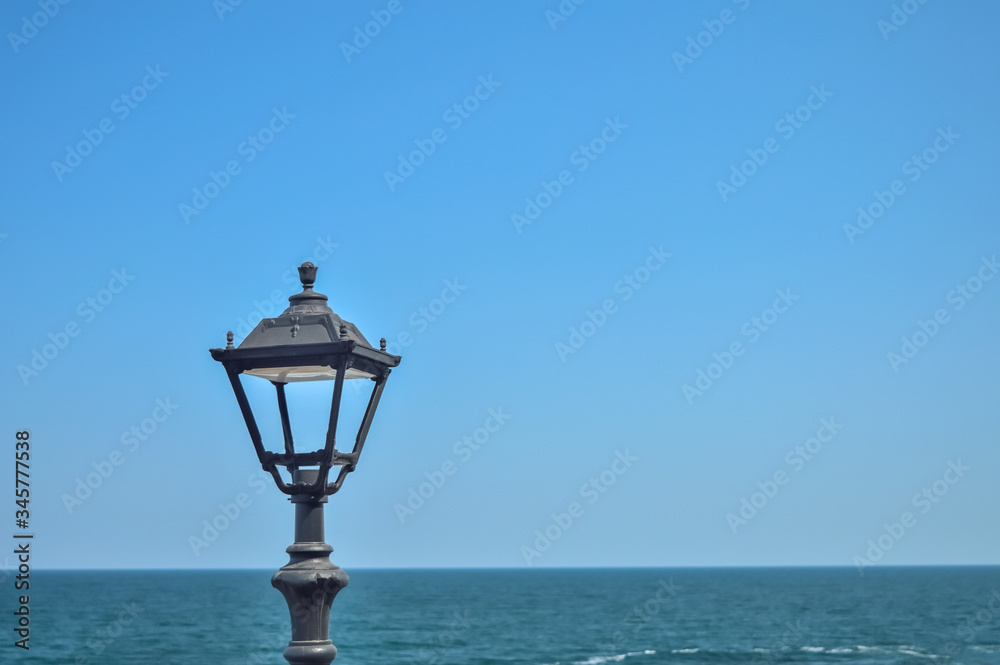 black antique street light on a background of blue seascape