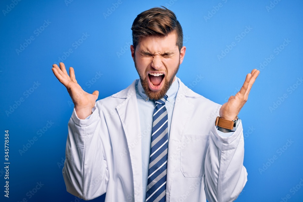 Young blond therapist man with beard and blue eyes wearing coat and tie over background celebrating mad and crazy for success with arms raised and closed eyes screaming excited. Winner concept Young blond therapist man with beard and blue eyes wearing coat and tie over background celebrating mad and crazy for success with arms raised and closed eyes screaming excited. Winner concept
