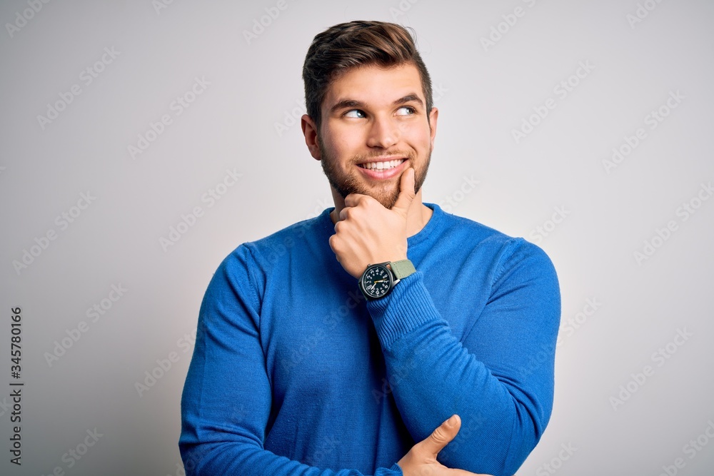 Young handsome blond man with beard and blue eyes wearing casual sweater with hand on chin thinking about question, pensive expression. Smiling with thoughtful face. Doubt concept. Young handsome blond man with beard and blue eyes wearing casual sweater with hand on chin thinking about question, pensive expression. Smiling with thoughtful face. Doubt concept.