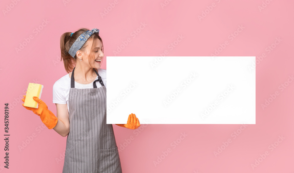 Smiling young housekeeper woman holding white blank placard and sponge Smiling young housekeeper woman holding white blank placard and sponge