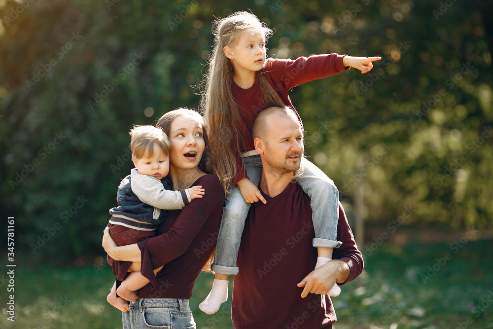 Fototapeta premium Family in a autumn park. Woman in a red sweater. Cute childrens with parents