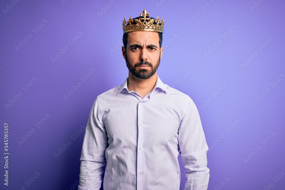 Young handsome man with beard wearing golden crown of king over purple background skeptic and nervous, frowning upset because of problem. Negative person. Young handsome man with beard wearing golden crown of king over purple background skeptic and nervous, frowning upset because of problem. Negative person.