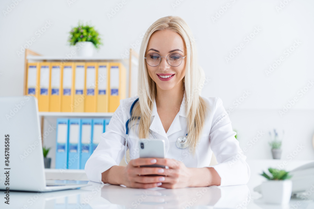 Close-up portrait of her she nice attractive confident cheerful focused girl doc cardiologist surgeon stethoscope giving advice using device app visit web in modern light white workplace workstation Close-up portrait of her she nice attractive confident cheerful focused girl doc cardiologist surgeon stethoscope giving advice using device app visit web in modern light white workplace workstation