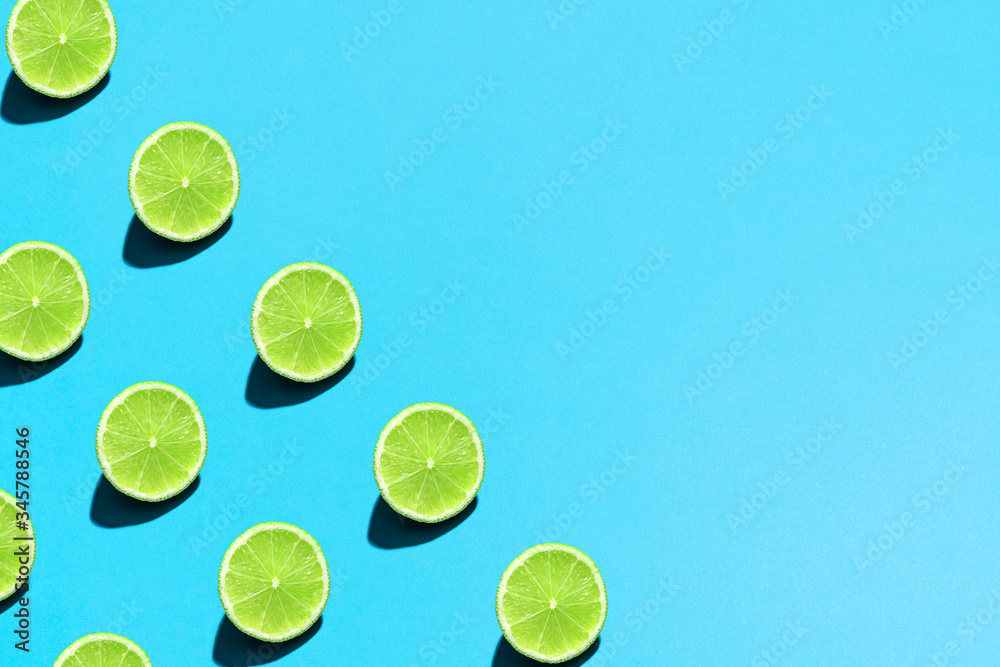 Minimal flat lay food texture. Summer abstract trendy fresh concept. Lime pattern on bright light blue background, copy space.