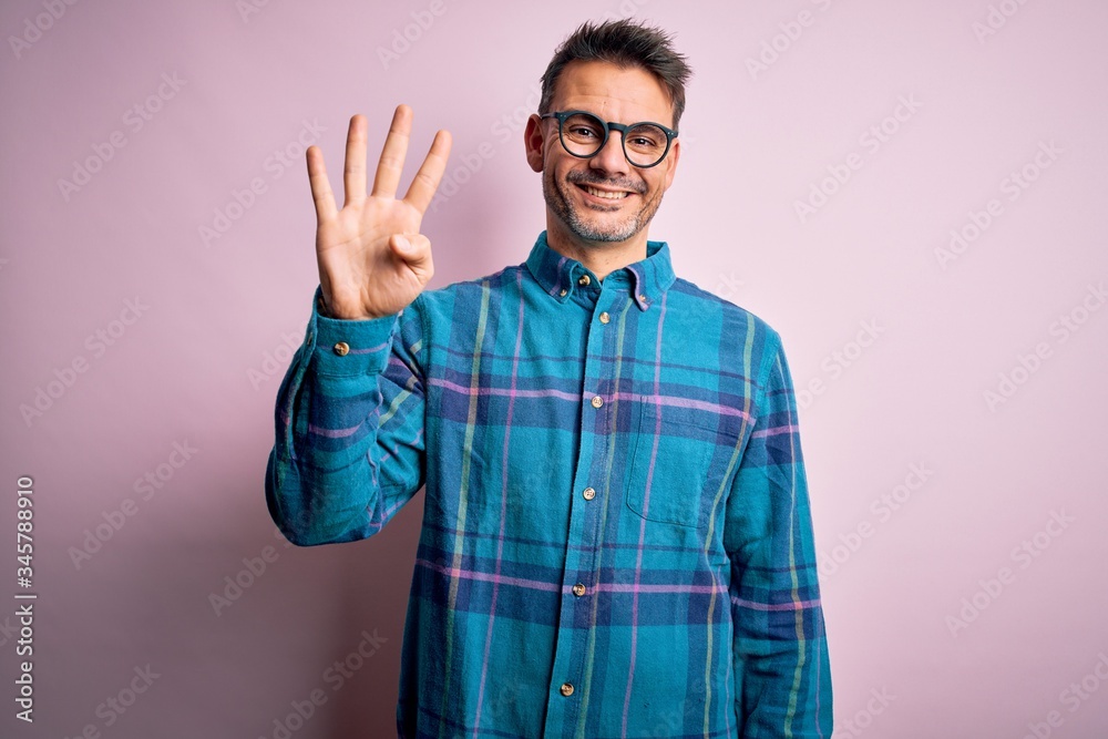 Young handsome man wearing casual shirt and glasses standing over isolated pink background showing and pointing up with fingers number four while smiling confident and happy. Young handsome man wearing casual shirt and glasses standing over isolated pink background showing and pointing up with fingers number four while smiling confident and happy.