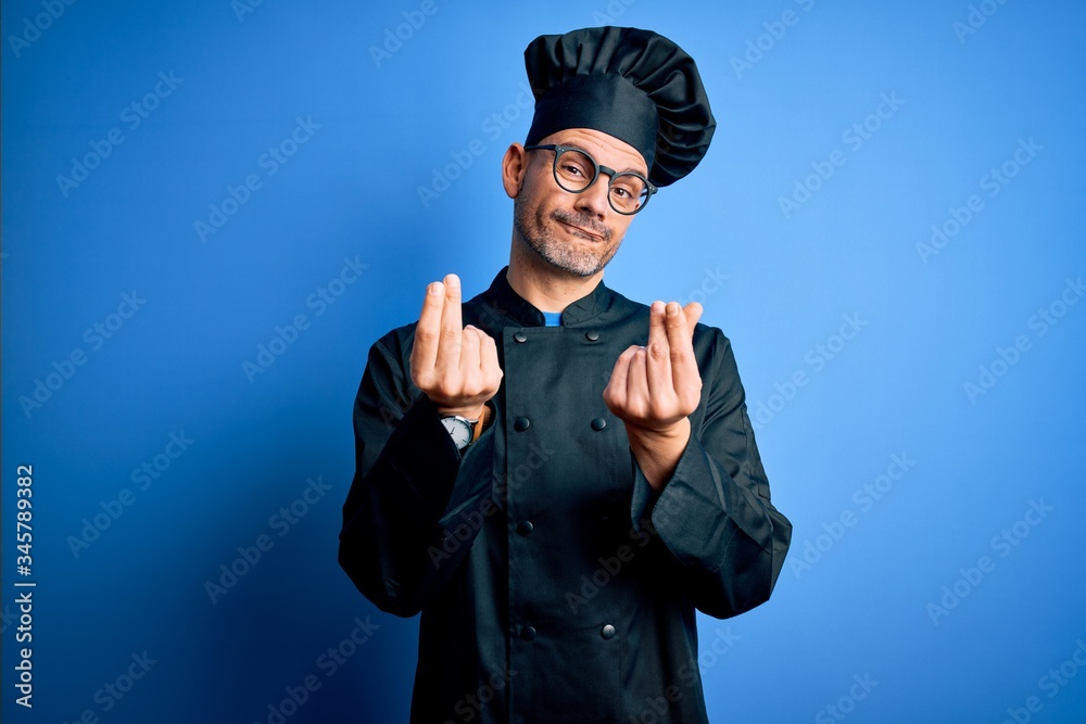 Young handsome chef man wearing cooker uniform and hat over isolated blue background doing money gesture with hands, asking for salary payment, millionaire business Young handsome chef man wearing cooker uniform and hat over isolated blue background doing money gesture with hands, asking for salary payment, millionaire business