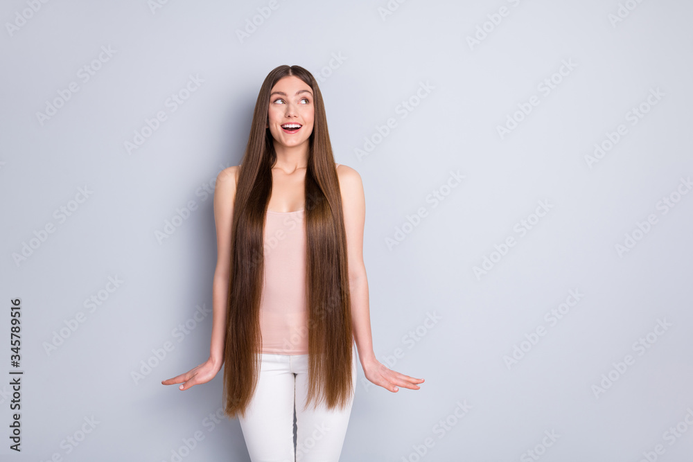 Obraz premium Photo of charming appearance model lady demonstrating ideal neat long hairstyle look interested side empty space wear singlet white trousers isolated grey color background