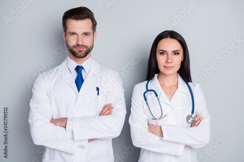 Photo of handsome doc guy professional lady patients consultation virology clinic listen client complaining arms crossed confident doctors wear lab coats isolated grey color background