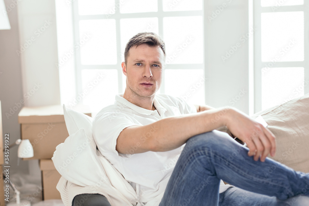 happy man sitting on the couch in his new apartment happy man sitting on the couch in his new apartment