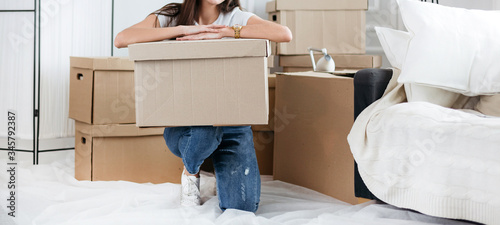 young woman with a cardboard box sitting on the floor in a new apartment