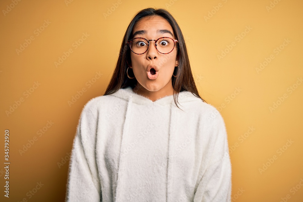 Young beautiful asian woman wearing casual sweater and glasses over yellow background afraid and shocked with surprise expression, fear and excited face. Young beautiful asian woman wearing casual sweater and glasses over yellow background afraid and shocked with surprise expression, fear and excited face.