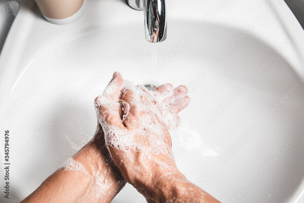 Fototapeta premium Person washing their hands with soap and hot water in the home sink wash. Cleaning the hygiene of the hand to prevent outbreaks of coronavirus. 