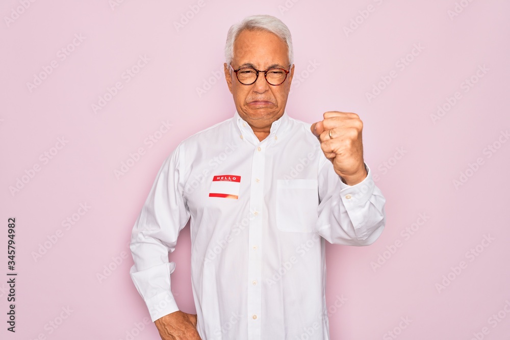 Middle age senior grey-haired man wearing hello my name is introduction sticker annoyed and frustrated shouting with anger, crazy and yelling with raised hand, anger concept